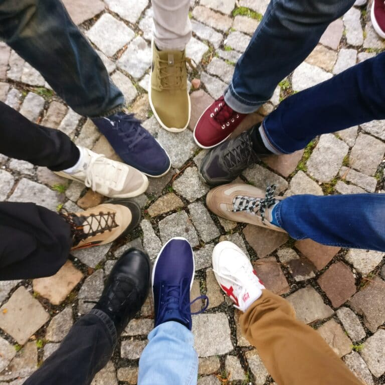 Eight pairs of shoes arranged in a circle on cobblestones