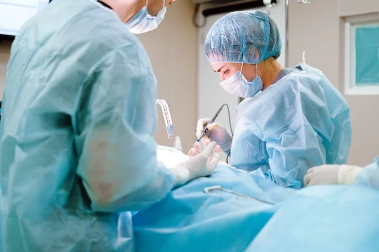 Two surgeons in gowns and caps operating with an electrosurgical instrument