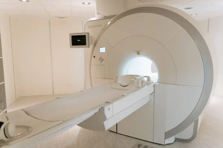 An empty MRI scanner with its patient table extended in a clinical room