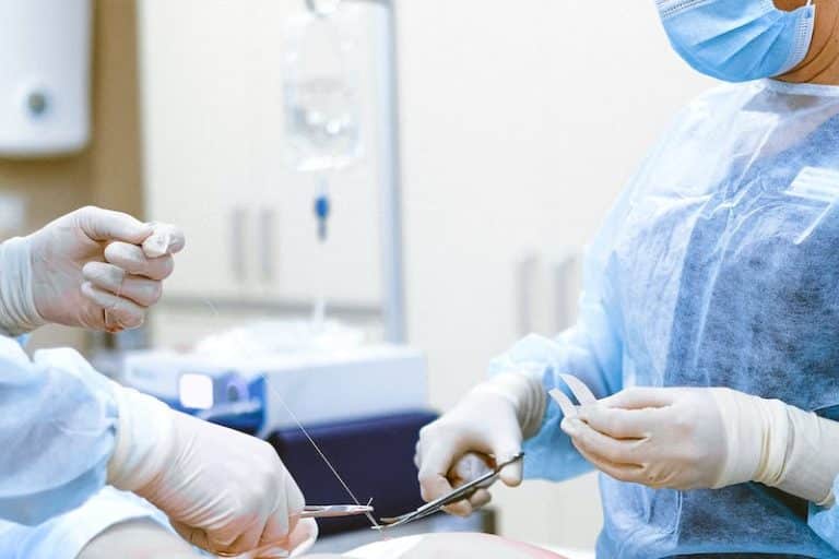 Two gowned surgeons passing suture and instruments during an operation