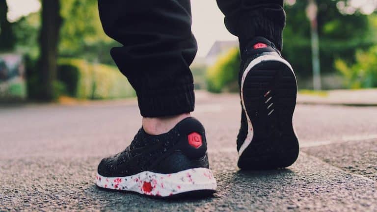 Close-up of a runner's black and white trainers mid-stride on a road