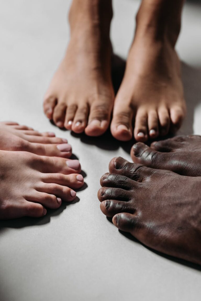 Three pairs of bare feet of different skin tones arranged on a pale floor