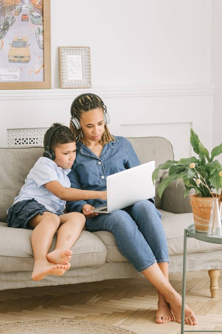 Parent and child sitting barefoot on a sofa sharing a laptop