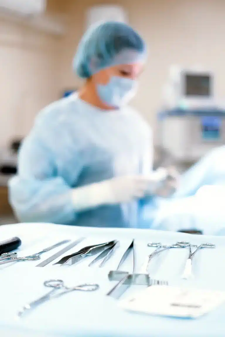 Surgical instruments on a blue drape with a gowned theatre nurse behind