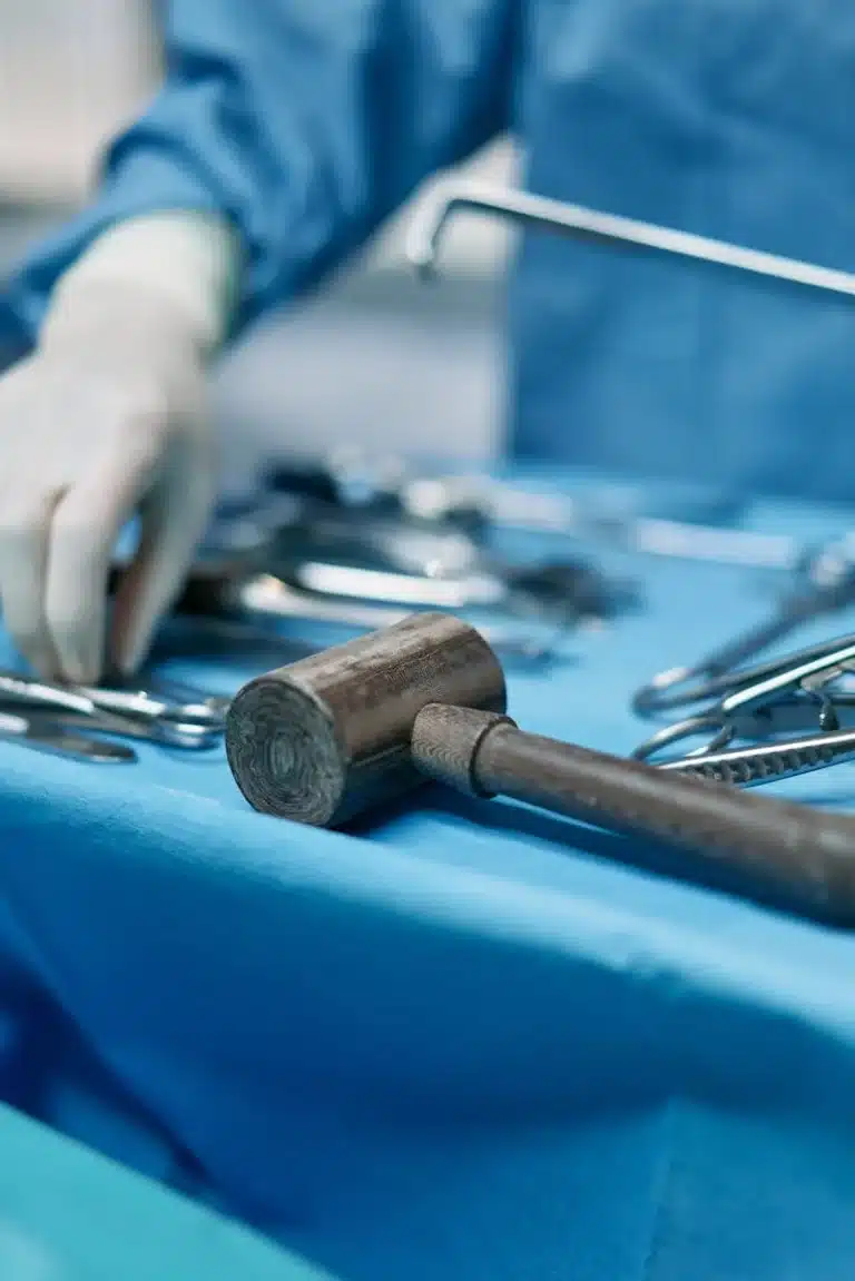 Surgical instruments including a bone mallet laid out on a blue drape in an operating theatre