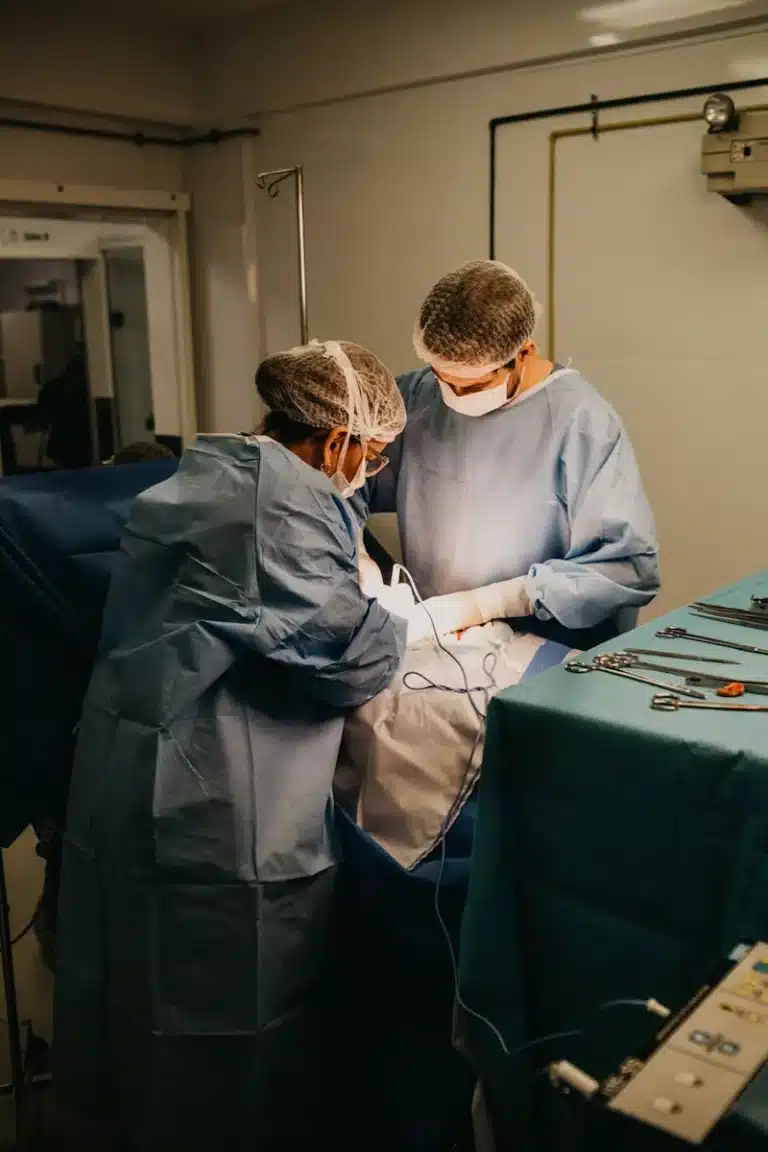 Two surgeons in gowns and caps operating over a draped patient