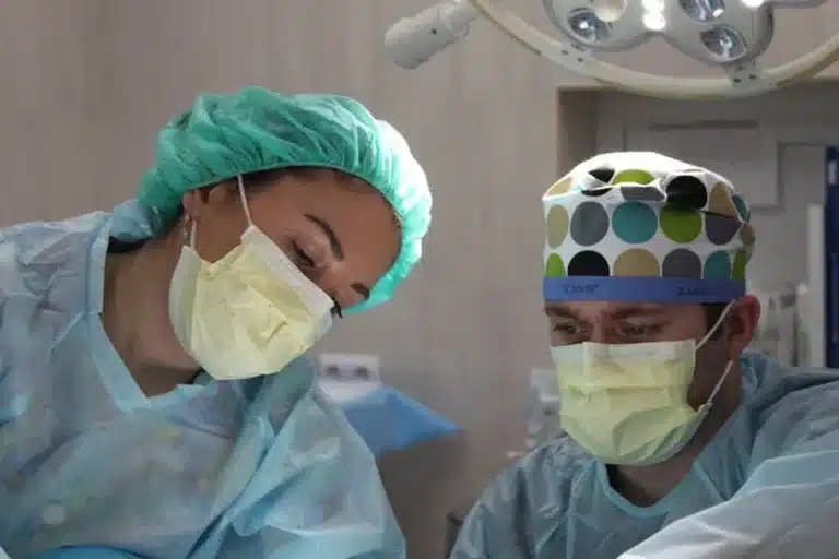 Two surgeons in caps and masks looking down during an operation
