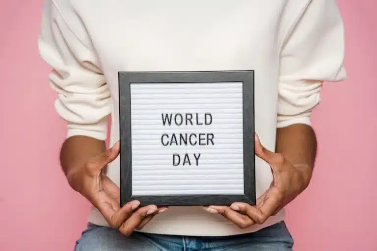Person holding a letterboard sign reading World Cancer Day against a pink background