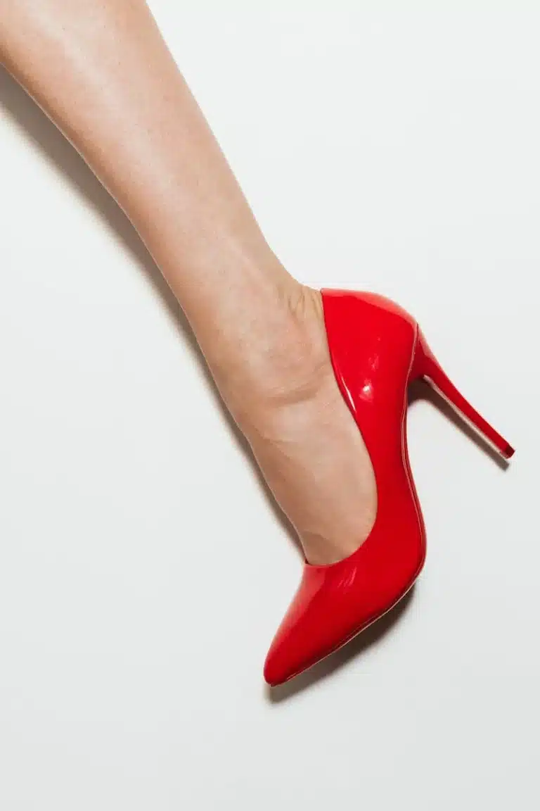 A woman's foot wearing a red patent high-heeled court shoe